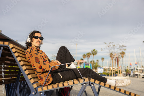 Relaxed man enjoying music at seaside bench with headphones photo