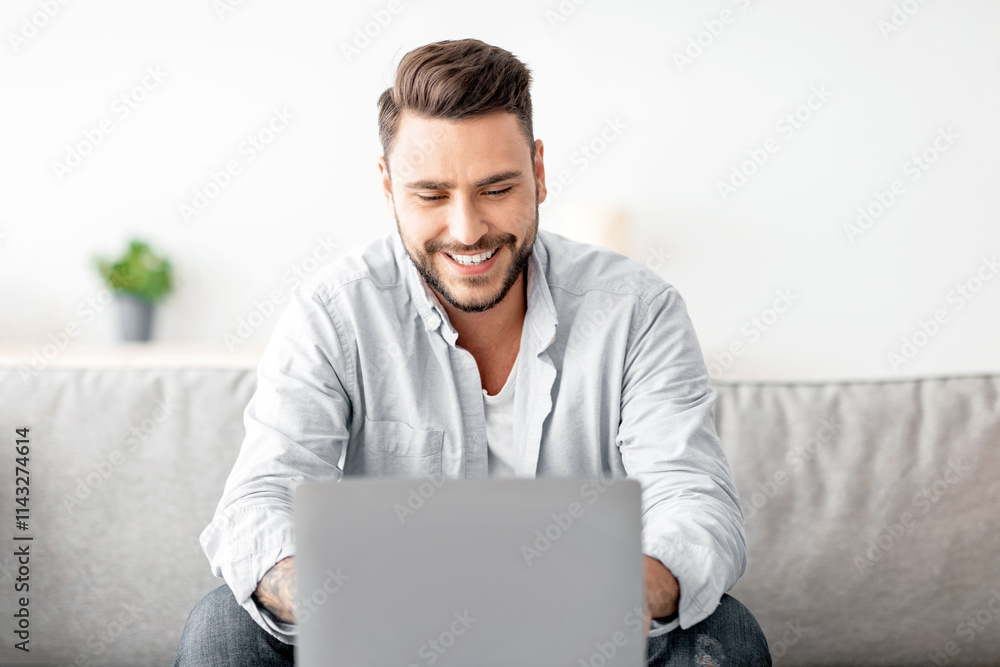 Recruitment concept. Happy millennial guy browsing work opportunities online, using job search app or website on laptop, sitting on sofa at home, free space Recruitment concept. Happy millennial guy browsing work opportunities online, using job search app or website on laptop, sitting on sofa at home, free space