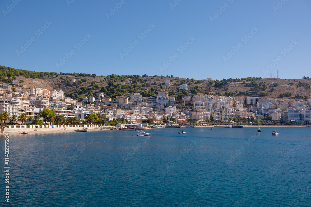 Resort town in Albania, view from a departing ship to houses and mountains. Port town of Saranda in Albania Resort town in Albania, view from a departing ship to houses and mountains. Port town of Saranda in Albania