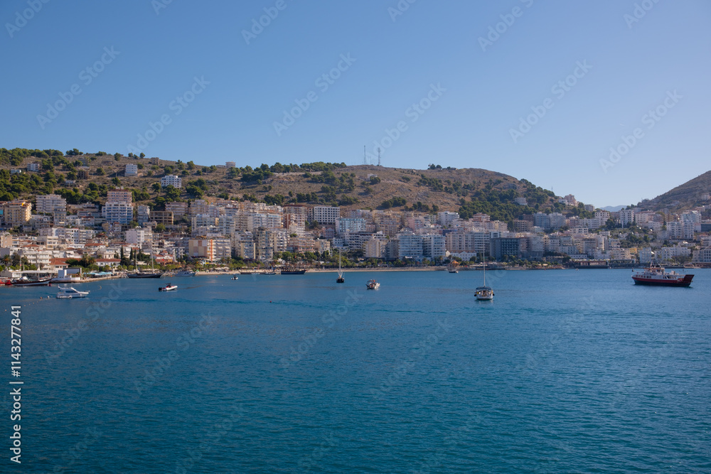 Resort town in Albania, view from a departing ship to houses and mountains. Port town of Saranda in Albania Resort town in Albania, view from a departing ship to houses and mountains. Port town of Saranda in Albania