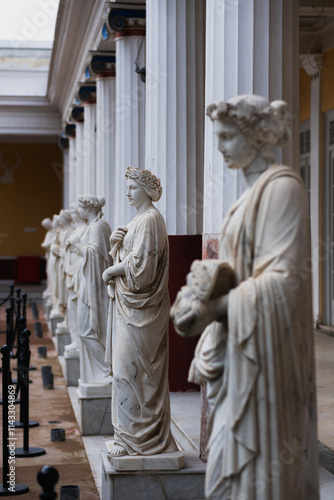 Antique statues of Women in Wreaths. The white stone statues stand in a neat row among Greek-style columns photo