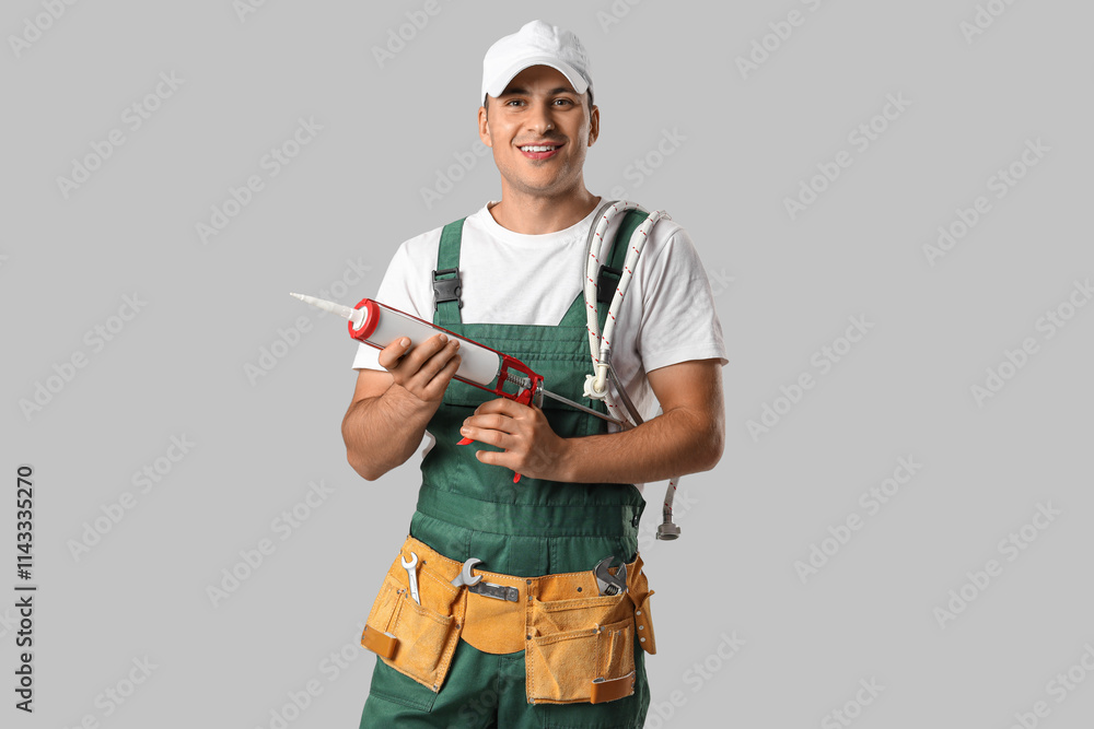 Male plumber with caulking gun on light background Male plumber with caulking gun on light background