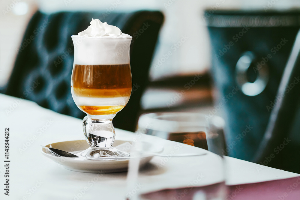 Aromatic coffee with syrup and whipped cream in a glass stands on a table in the restuarant. An idea for a sweet coffee dessert. Aromatic coffee with syrup and whipped cream in a glass stands on a table in the restuarant. An idea for a sweet coffee dessert.