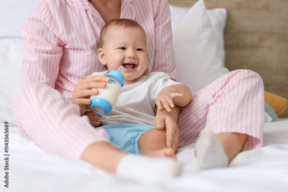 Mother feeding her cute little baby with milk from bottle in bedroom, closeup Mother feeding her cute little baby with milk from bottle in bedroom, closeup