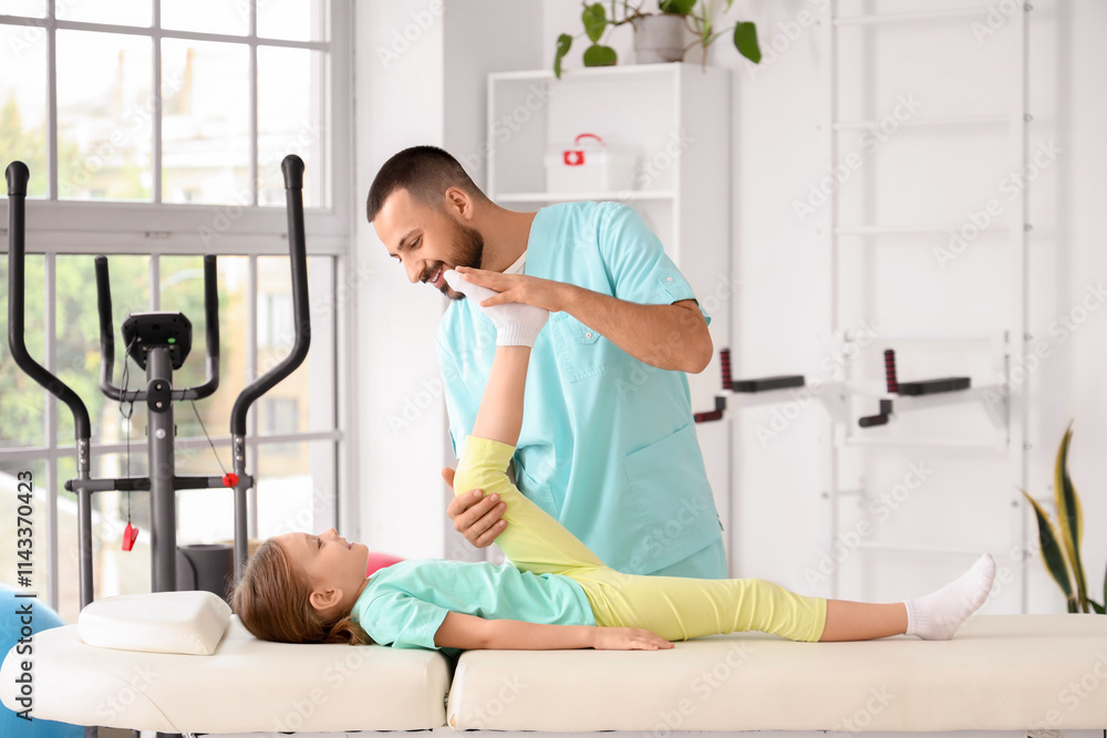 Male physiotherapist working with little girl lying on couch in rehabilitation center Male physiotherapist working with little girl lying on couch in rehabilitation center