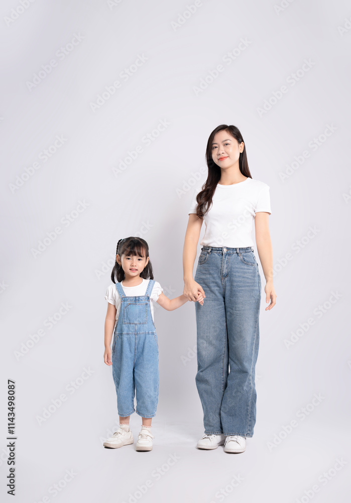 Full body image of Asian mother and daughter posing on white background Full body image of Asian mother and daughter posing on white background