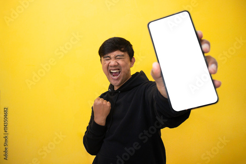 Winning expression man showing screen phone stand over yellow wall. photo