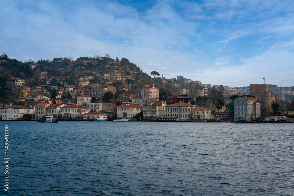 Fototapeta premium Anadolu Hisari neighborhood in Beykoz district against the background of the Anatolian Fortress from the waters of the Bosphorus Strait on a sunny day, Istanbul, Turkey