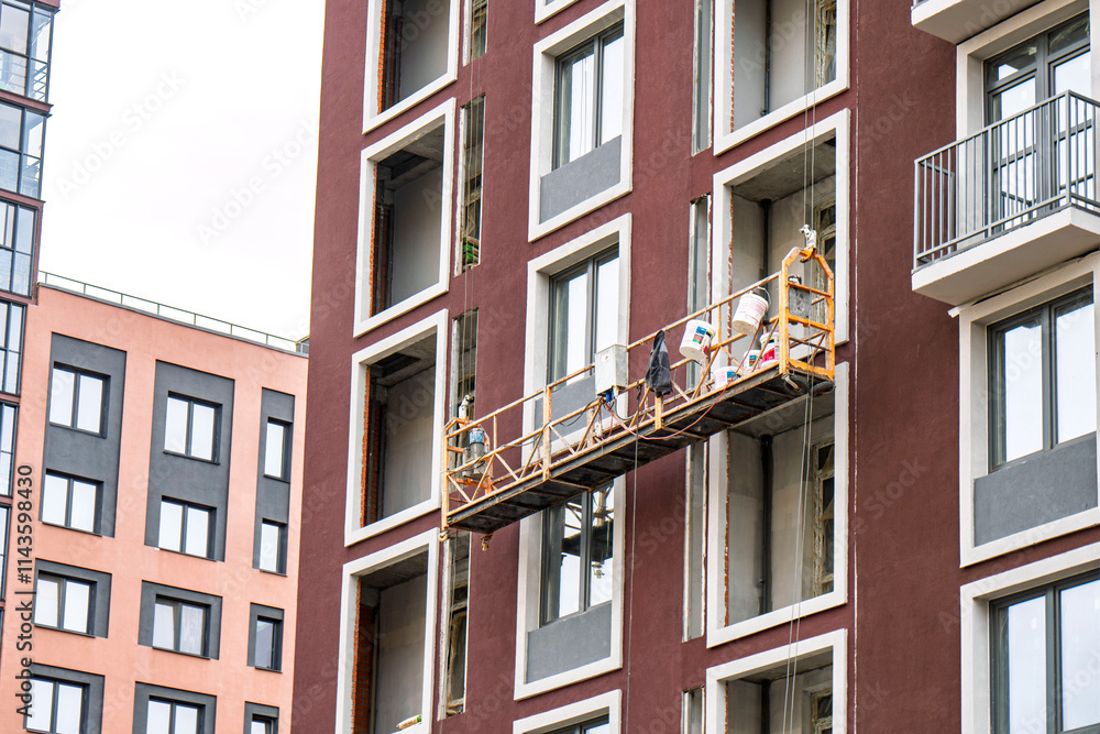 Naklejka premium Construction scaffold suspended in front of a modern building facade with windows, showcasing exterior renovation work