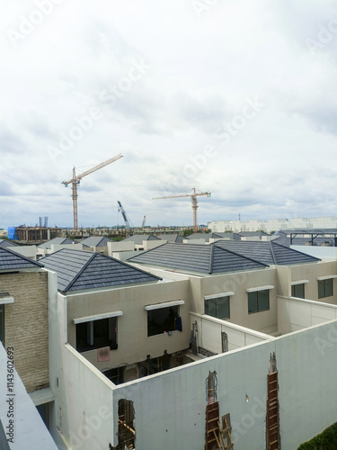 Jakarta, Indonesia - December 11, 2024: New housing development is underway, with rows of roofs already installed and a construction crane visible in the distance. photo