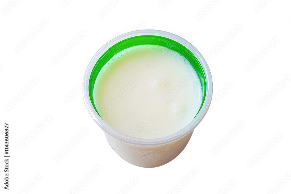 a small clear plastic cup with a green rim filled with white liquid the cup is sitting on a white surface a small clear plastic cup with a green rim filled with white liquid the cup is sitting on a white surface