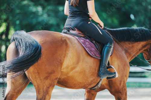 A woman in riding attire sits on a brown horse with a purple saddle pad, enjoying a serene ride outdoors. The image captures a peaceful horseback riding moment in nature.