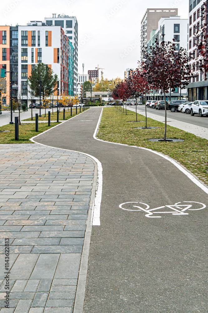 Urban bike path with white bike symbol, surrounded by red-leaved trees and modern buildings, showcasing city infrastructure Urban bike path with white bike symbol, surrounded by red-leaved trees and modern buildings, showcasing city infrastructure