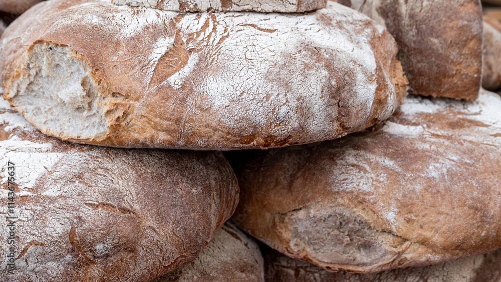 Loaves of artisanal brown bread are stacked high in a rustic bakery. The crusty exterior reveals the craftsmanship behind each piece, embodying warmth and tradition in baking. Loaves of artisanal brown bread are stacked high in a rustic bakery. The crusty exterior reveals the craftsmanship behind each piece, embodying warmth and tradition in baking.
