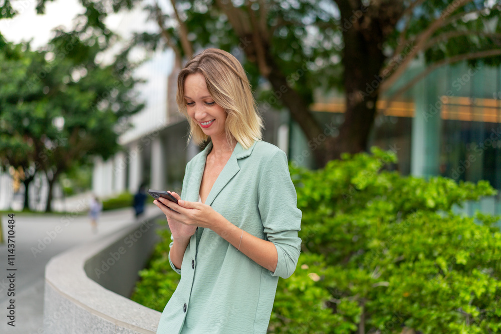 Confident White Businesswoman Using Phone In Front of Modern Glass Office Building with Lush Green Background Confident White Businesswoman Using Phone In Front of Modern Glass Office Building with Lush Green Background