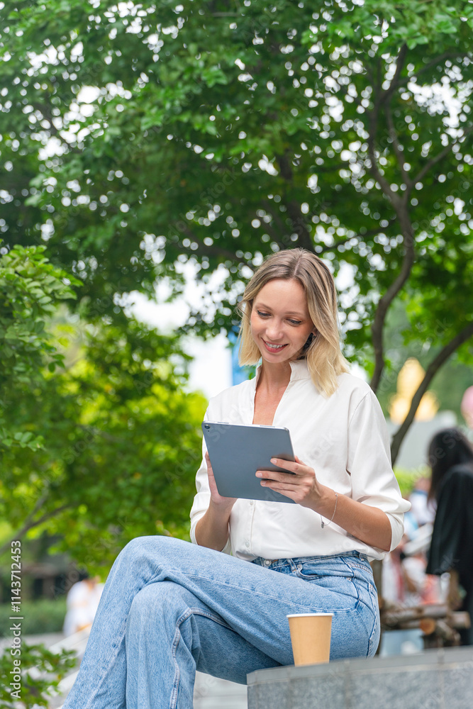 Caucasian Woman Sitting and Using Tablet While Having a Cup of Coffee Outdoor a Park Caucasian Woman Sitting and Using Tablet While Having a Cup of Coffee Outdoor a Park