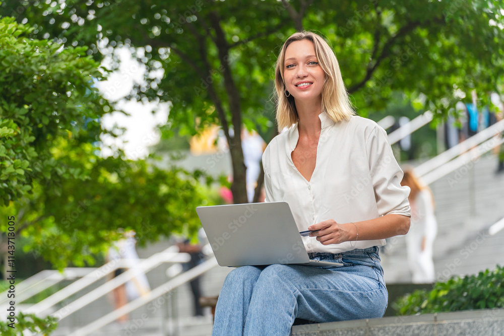 Caucasian Woman Using Laptop and Credit Card to Perform Online Transaction While Sitting Outdoor a Park Caucasian Woman Using Laptop and Credit Card to Perform Online Transaction While Sitting Outdoor a Park