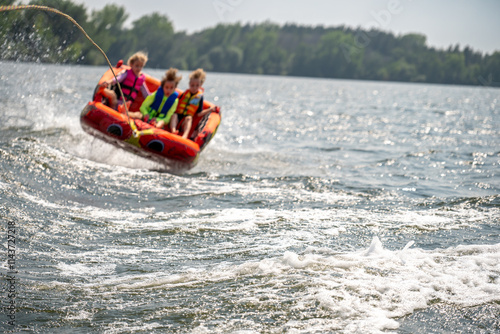Inflatable raft being pulled at a high speed by a boat in a recreational activity called tubing