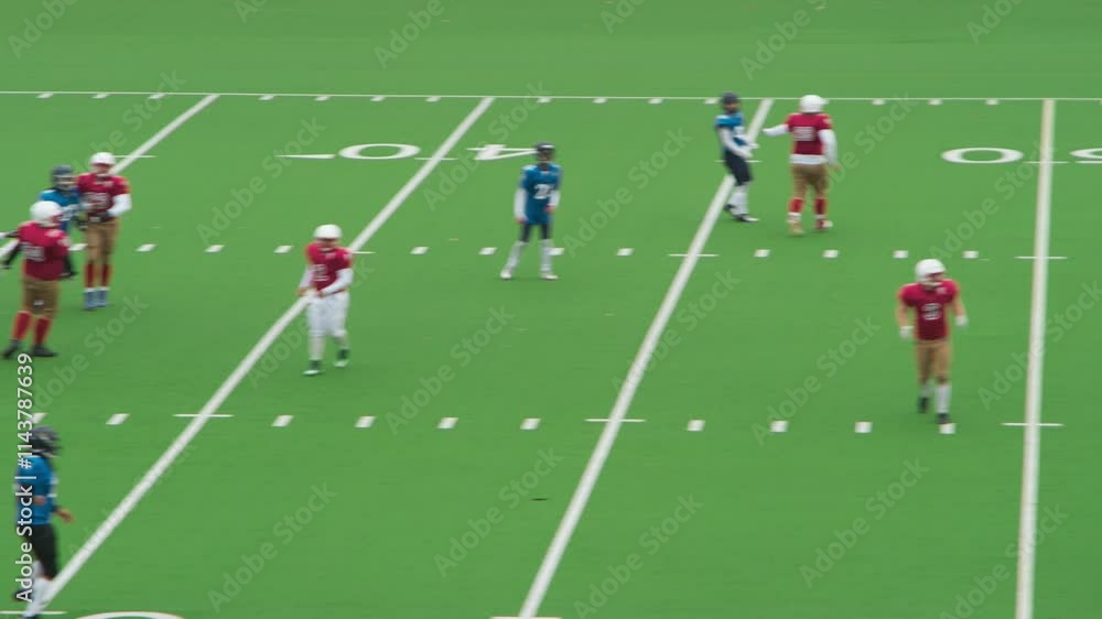 Diverse Male Athletes in Red and Blue Jerseys Compete in an American Football Game. Motivated Players Clash for Control on the Field, Executing Precise Throws and Dynamic Runs Diverse Male Athletes in Red and Blue Jerseys Compete in an American Football Game. Motivated Players Clash for Control on the Field, Executing Precise Throws and Dynamic Runs