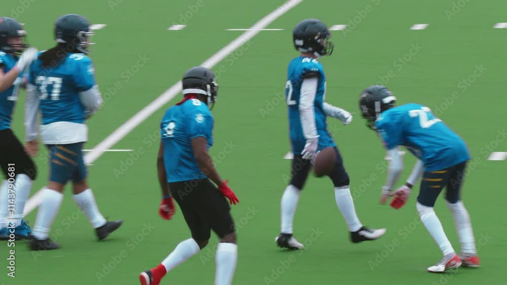 Excited Diverse Team of American Football Players Jumping on Stadium Field. Team of Footballers in Blue Jerseys Celebrating a Victory, Raising Arms, Cheering Together with Emotional Sport Fans