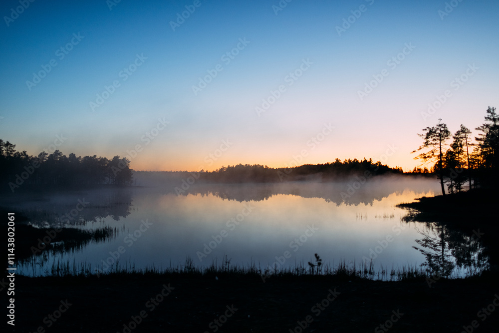 Fototapeta premium Tranquil Lake Reflection at Sunrise with Misty Horizon