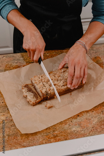 Baker cutting coffee cake loaf on counter