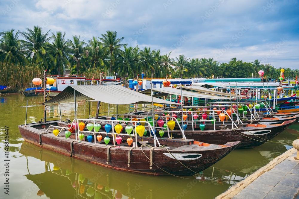 Obraz premium Colorful traditional Vietnamese boats decorated with lanterns lined up on the riverbank in Hoi An