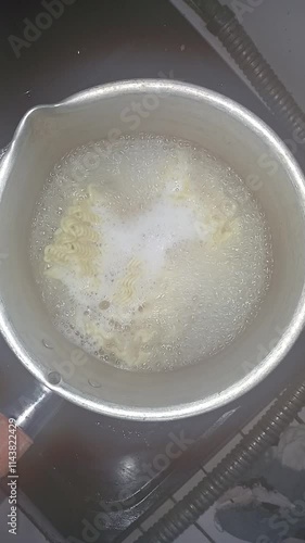 view of instant noodles being boiled in a small pan. Cooking concept.