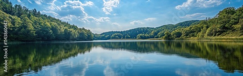 Mountain lake reflects vibrant blue sky and lush green forests under soft sunlight during a tranquil day