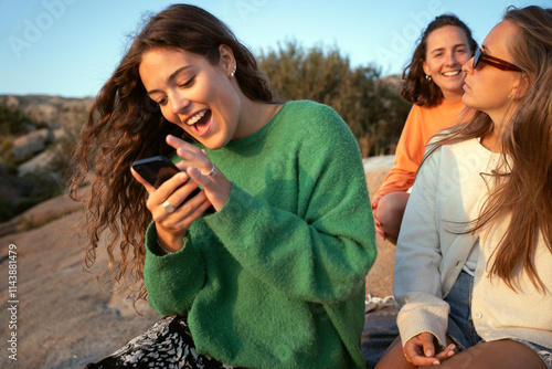 Wallpaper Mural Cheerful young woman using mobile phone while sitting with female friends at picnic Torontodigital.ca