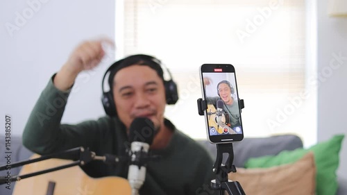 Asian Male Musician Ends Live Guitar Tutor Video Broadcast And Say Goobye To Audience From Mobile Phone photo