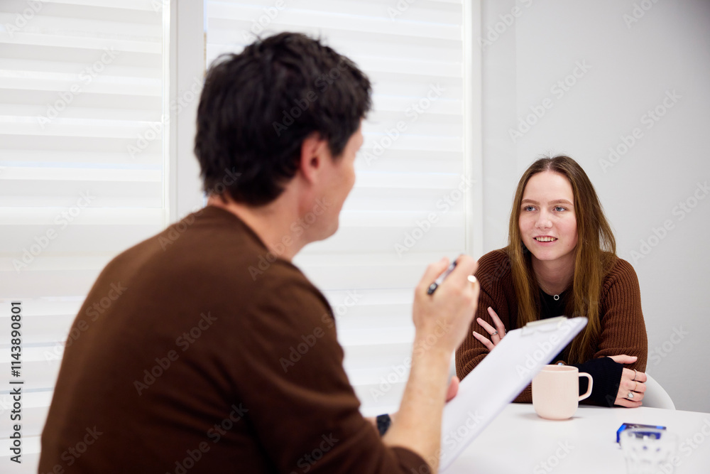 Male healthcare worker conducting interview of female student Male healthcare worker conducting interview of female student