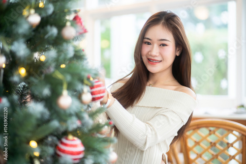 Obraz na płótnie Portrait of beautiful happy Smiling asian woman relaxing sitting decorating to a Christmas tree at home in the living room indoors Decoration During Christmas x-mas and New Year holidays. w salonie