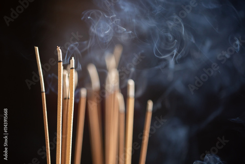 Close up of incense sticks smoking against a dark background