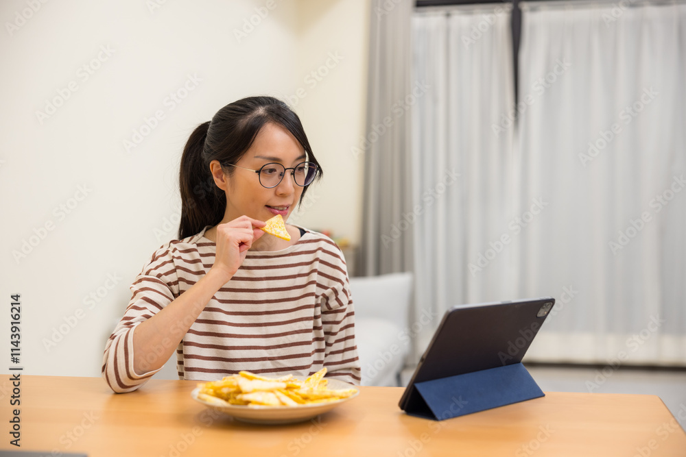 Woman watching video on tablet and eating snacks Woman watching video on tablet and eating snacks