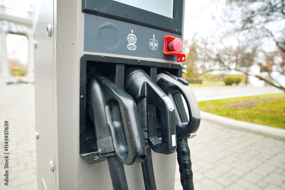 Fototapeta premium EV charger plugs close-up. Electric vehicle charging station with plug-in connectors in city street. Clean energy, renewable power, and sustainability. Selective focus
