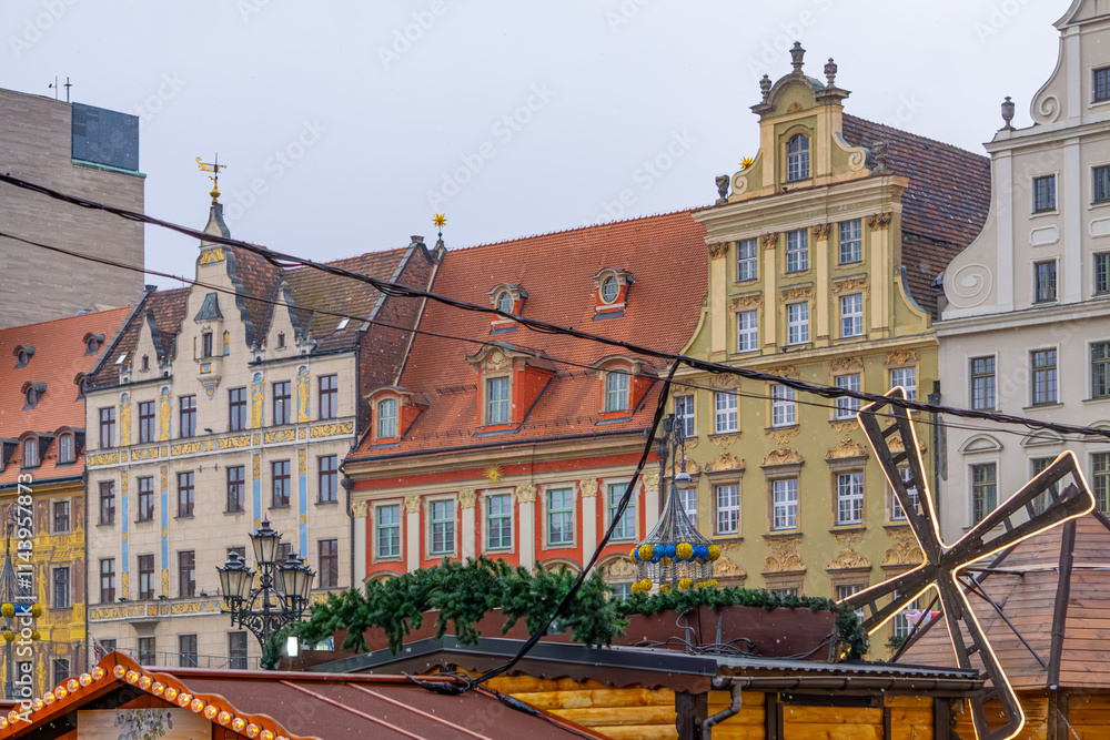 Obraz premium stalls at a Christmas and New Year's market in a big city. Christmas tree decorations and decorations, lights, baubles, garlands against the background of urban architecture, old historic tenement hou
