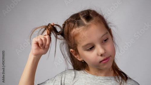 Cute girl twirling her hair around her fingers and thinking with smile on her face