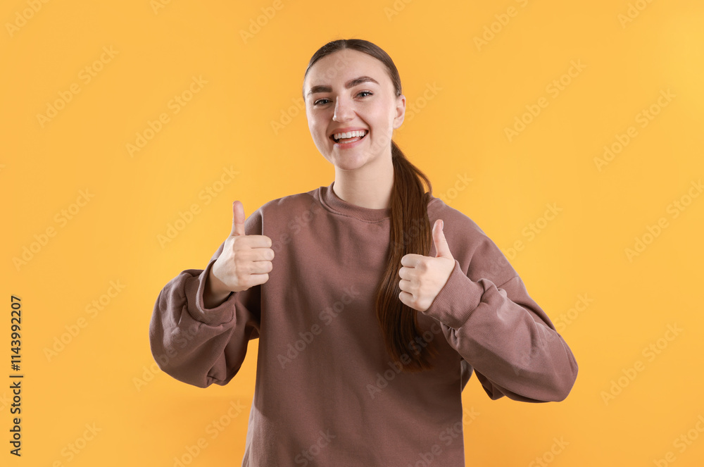 Happy woman showing thumbs up on yellow background. Like gesture Happy woman showing thumbs up on yellow background. Like gesture