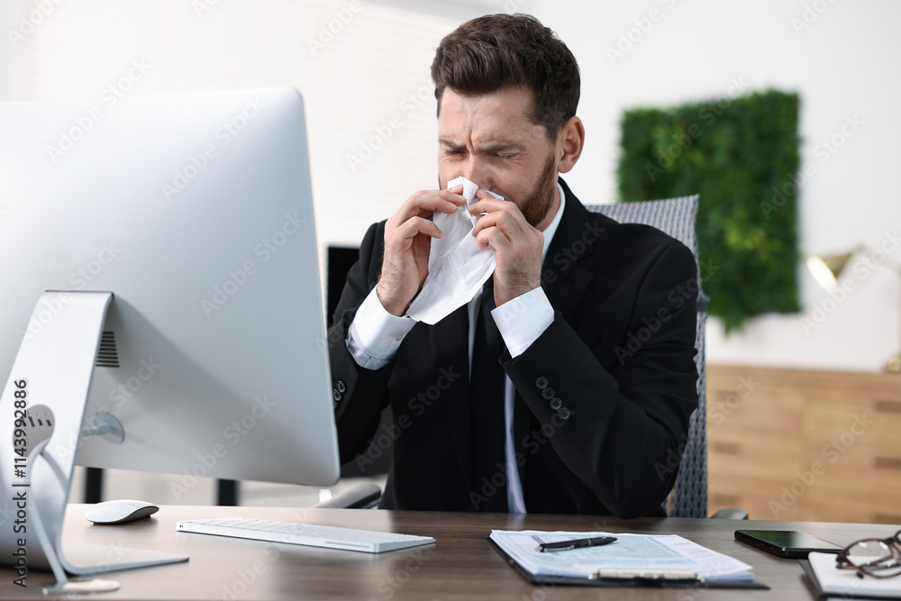 Sick man with runny nose at table in office Sick man with runny nose at table in office