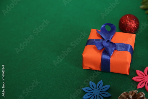 Season's greetings scene.Share your warm wishes with this image idea.view of magnificent giftbox with ribbon, sparkling ornaments, frosty fir, ball, cone on green backdrop, ready for personalized ad photo