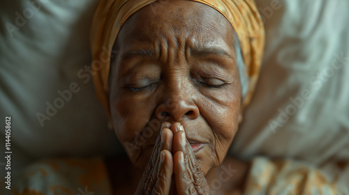 Elderly African woman praying with deep expression at home in peaceful surroundings photo