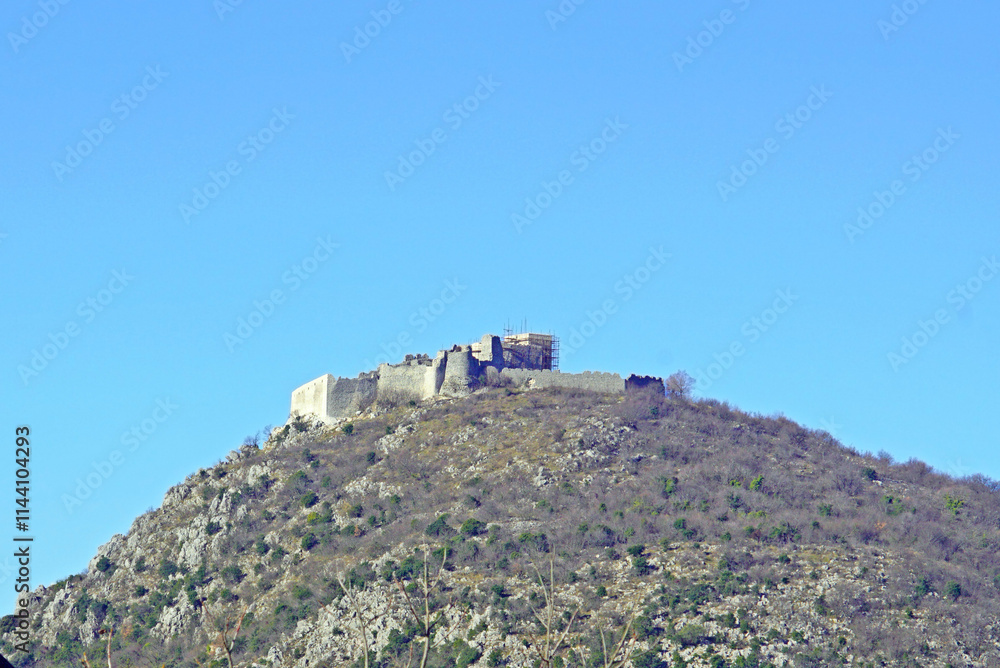 Ancient fortifications of Bosnia and Herzegovina: Herceg Stjepan's Fortress against the blue sky. Standing on the top of a mountain, the medieval Ljubuški Fortress - a general view from a distance. Ancient fortifications of Bosnia and Herzegovina: Herceg Stjepan's Fortress against the blue sky. Standing on the top of a mountain, the medieval Ljubuški Fortress - a general view from a distance.