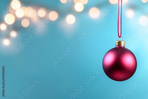 Red Christmas bauble hanging against a bokeh background.