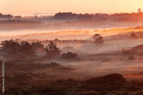 Beautiful sunrise at Lighthouse of Rubjerg Knude. Denmark north coast with wonderfully illuminated fog.