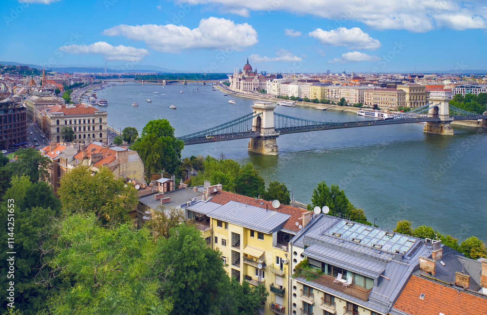 View of Budapest, residential buildings in the foreground, the Szechenyi Bridge over the Danube River, and the Pest side of the city with the Hungarian Parliament Building in the background