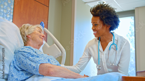 Female Doctor With Stethoscope Visiting Senior Female Patient In Hospital Bed Giving Her Good News photo