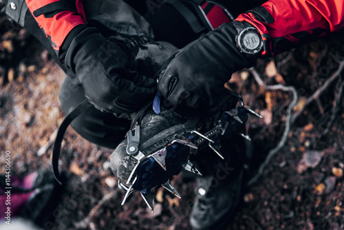 Rock climber puts on climbing shoes, man fasten crampons on his feet photo