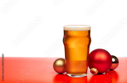 A pint glass of beer with festive Christmas baubles on a red and white background photo