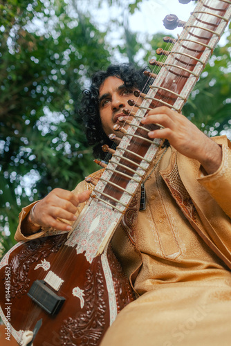 Indian musician in traditional clothes playing sitar festive season outdoor home. Happy Diwali greeting photo. Part of a series photo